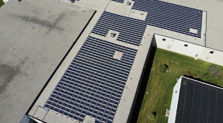 The featured image is an aerial view of a building with rooftop solar panels. 